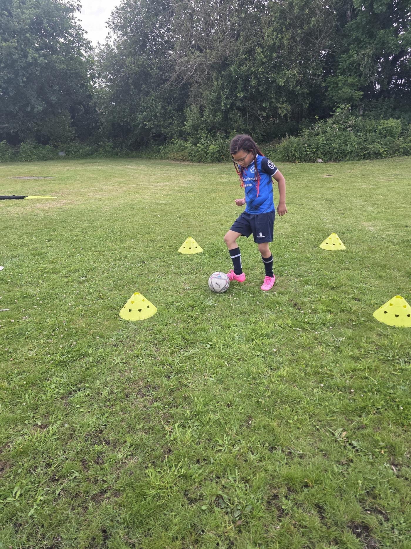 Young athlete Evelyn training ball control through cones during session